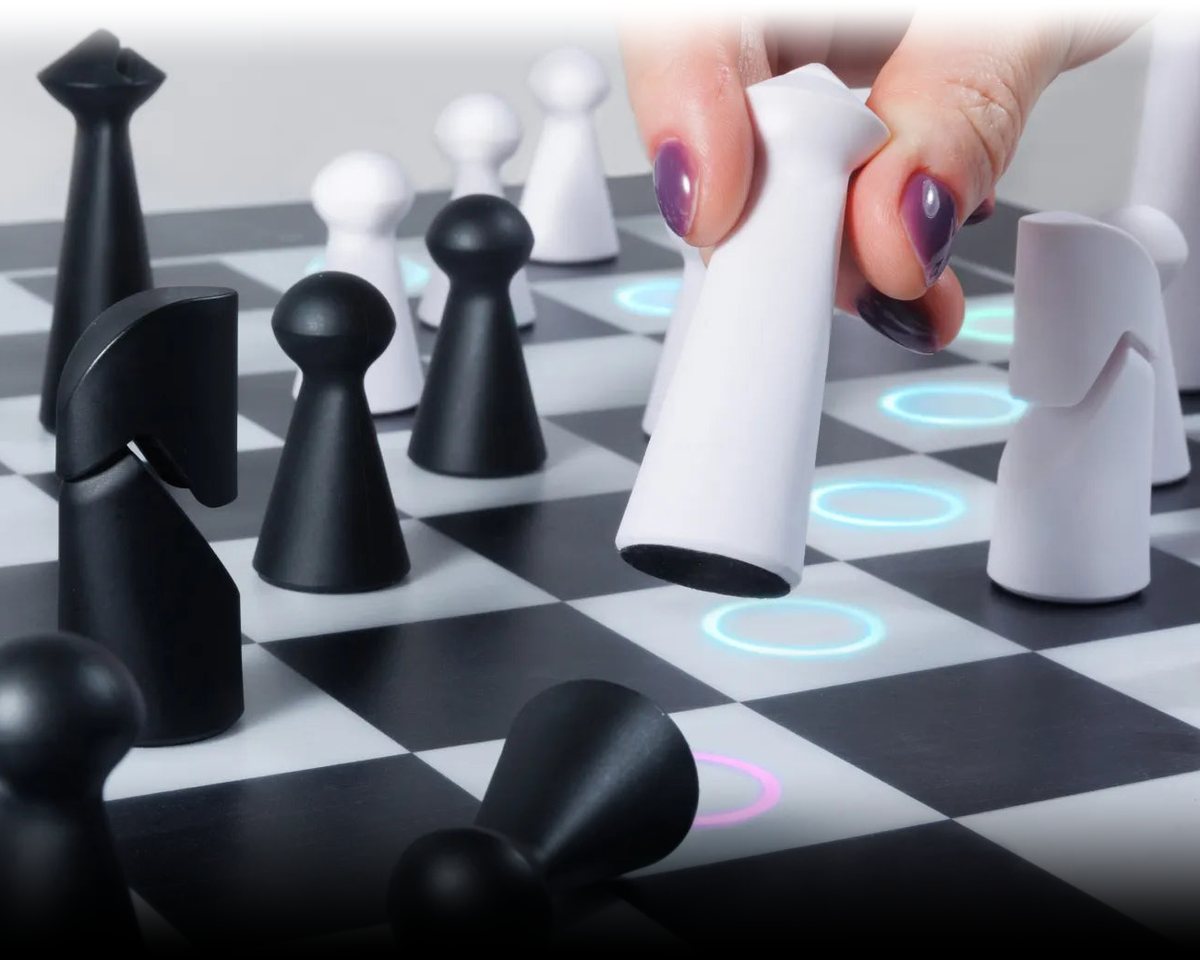 A hand moves a white piece on a GoChess board while lit rings mark the squares